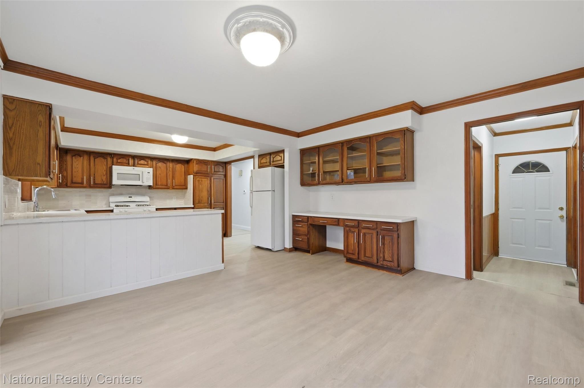 37625 Ryan Road Sterling Heights, MI 48310 - Photo 10 of 30 Kitchen with built in study area, crown molding, light countertops, wood finish cabinetry, and white appliances