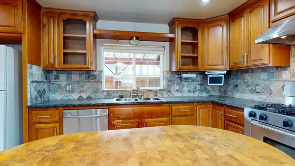 a kitchen with stainless steel appliances granite countertop a sink a stove cabinets dining table and chairs