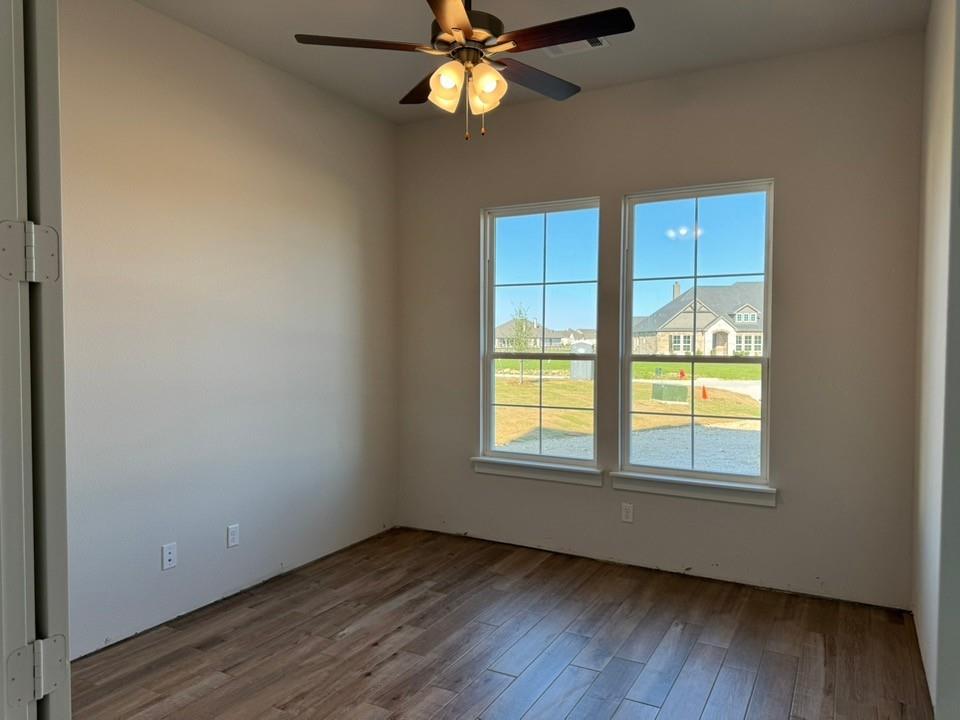 2209 Continent Court Krum, TX 76249 - Photo 7 of 24 an empty room with wooden floor fan and windows
