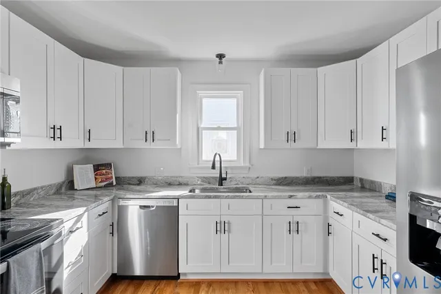 a kitchen with granite countertop a sink cabinets and stainless steel appliances