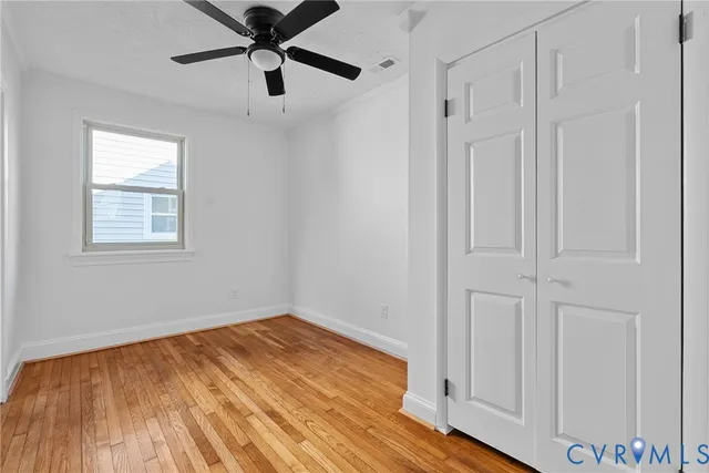 a view of empty room with wooden floor and fan