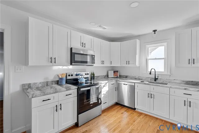 a kitchen with granite countertop white cabinets sink and stainless steel appliances