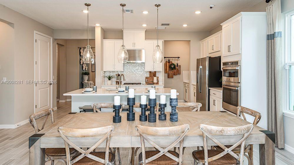653 Southeast Ranch Oak Circle Port St. Lucie, FL 34984 - Photo 11 of 43 a dining room with stainless steel appliances kitchen island granite countertop a dining table chairs and a refrigerator