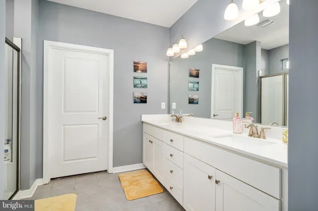 a spacious bathroom with a double vanity sink a mirror and a shower
