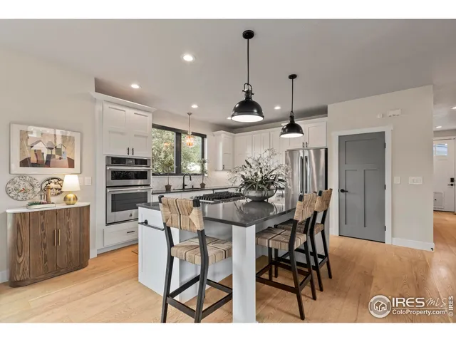 a kitchen with stainless steel appliances kitchen island granite countertop a dining table chairs and white cabinets