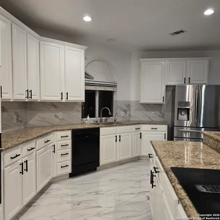 a kitchen with granite countertop white cabinets white stainless steel appliances and sink