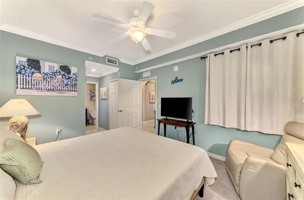 a bedroom with a bed table chair and a large window