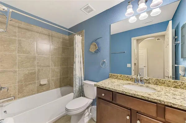 a bathroom with a granite countertop sink a mirror a toilet and bathtub