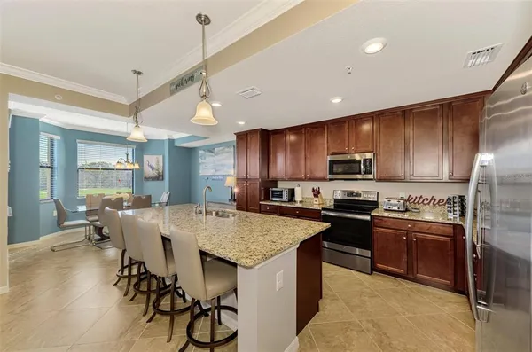 a kitchen with stainless steel appliances granite countertop table chairs stove and refrigerator