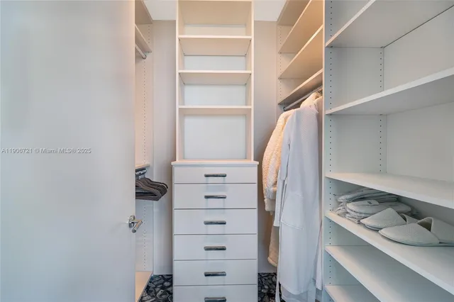 a view of walk in closet with clothes and shoes