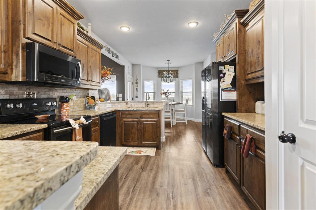 1195 Hog Town Road Collinsville, TX 76233 - Photo 11 of 37 a kitchen with stainless steel appliances granite countertop wooden cabinets a stove top oven a sink and dishwasher