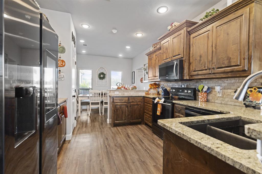 1195 Hog Town Road Collinsville, TX 76233 - Photo 9 of 37 a kitchen with stainless steel appliances granite countertop a refrigerator a sink dishwasher a stove and white cabinets with wooden floor