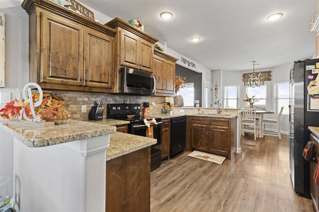 1195 Hog Town Road Collinsville, TX 76233 - Photo 10 of 37 a kitchen with stainless steel appliances granite countertop a stove top oven a sink dishwasher a dining table and chairs with wooden floor