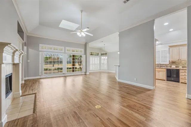 a view of an empty room with wooden floor and a kitchen