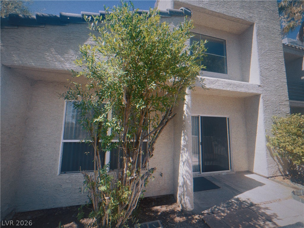 6250 West Flamingo Road, Unit 60 Las Vegas, NV 89103 - Photo 23 of 23 This dwelling features a stucco exterior, sliding glass door entrance, and a vibrant shrub providing natural screening.