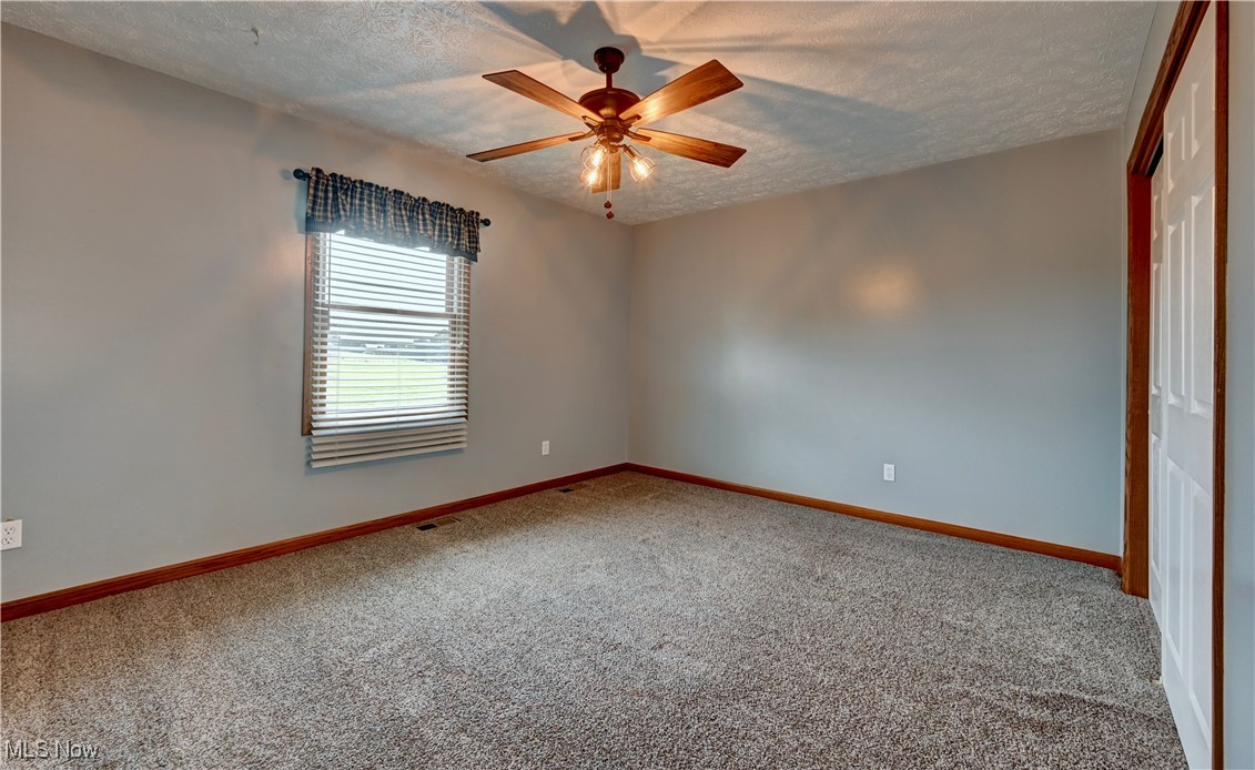 9559 Trail Bottom Road Northwest Dundee, OH 44624 - Photo 24 of 48 Carpeted empty room featuring a textured ceiling and ceiling fan