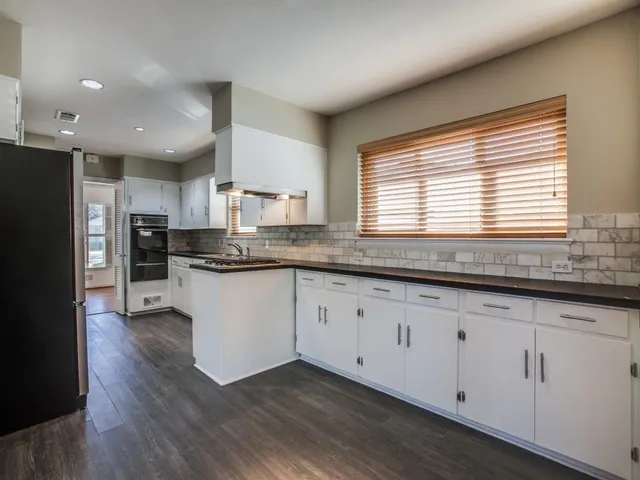 a kitchen with granite countertop stainless steel appliances a sink cabinets and a window