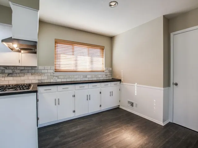 a kitchen with granite countertop white cabinets and a wooden floor