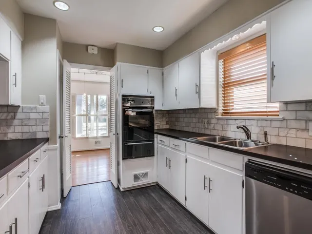 a kitchen with granite countertop a sink stove and cabinets