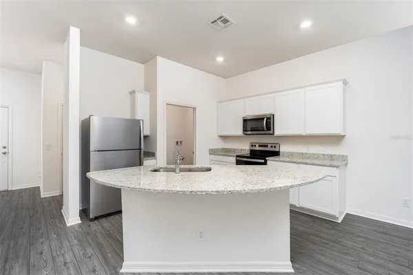 a kitchen with stainless steel appliances granite countertop a sink a microwave a refrigerator and a stove
