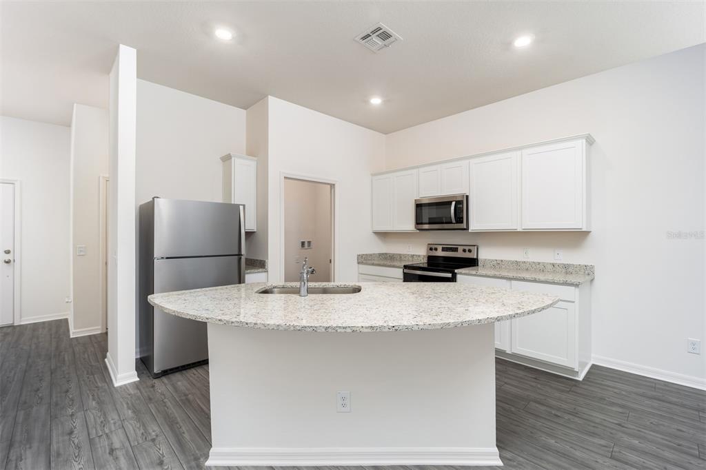 696 Poppy Lane Dundee, FL 33838 - Photo 4 of 16 a kitchen with stainless steel appliances granite countertop a sink a microwave a refrigerator and a stove