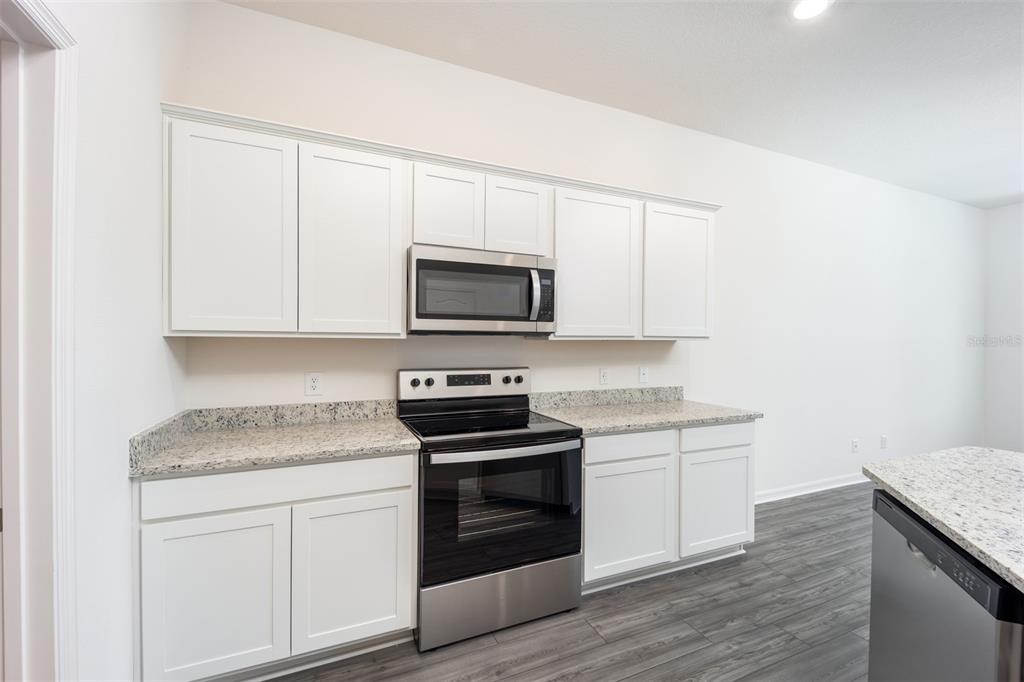 696 Poppy Lane Dundee, FL 33838 - Photo 5 of 16 a kitchen with granite countertop white cabinets and stainless steel appliances