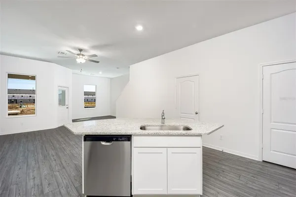 a room with kitchen island a sink wooden floor and white appliances