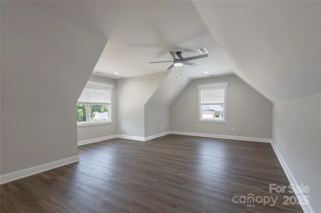 an empty room with wooden floor chandelier and windows