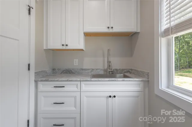 a kitchen with granite countertop white cabinets and a sink