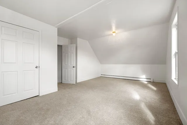 a view of an empty room with fire place and a window