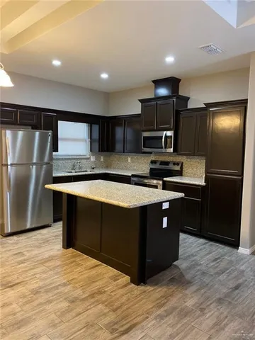 a kitchen with stainless steel appliances granite countertop a stove a refrigerator and a sink