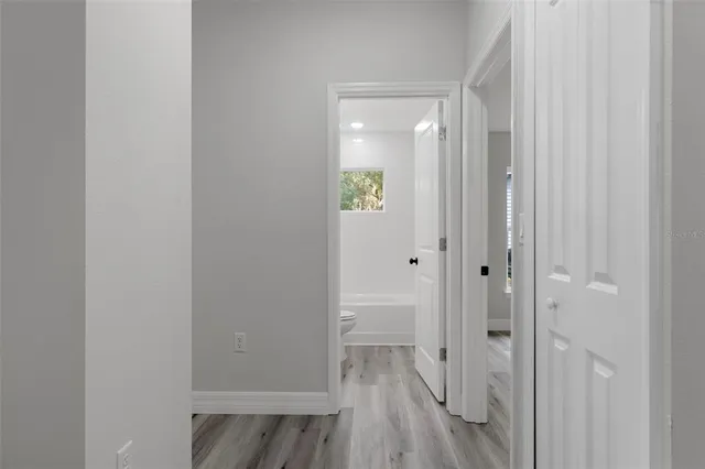 a kitchen with a sink dishwasher and white cabinets with wooden floor