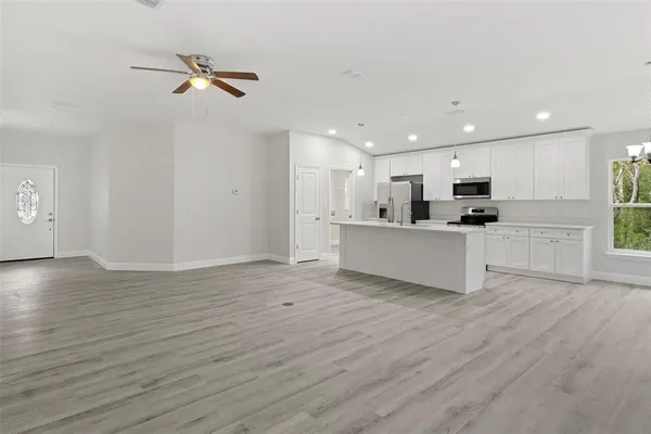 a kitchen with stainless steel appliances granite countertop a stove top oven a refrigerator a sink dishwasher and a fireplace with wooden floor