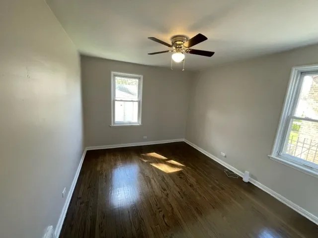 an empty room with wooden floor closet and windows