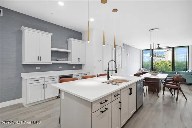 a kitchen with stainless steel appliances a sink a stove a refrigerator cabinets and wooden floor