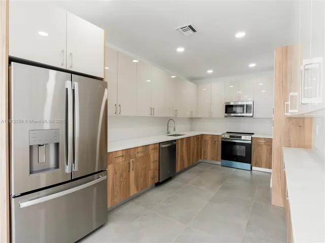 a large kitchen with stainless steel appliances granite countertop a refrigerator and a stove top oven