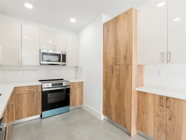 a kitchen with stainless steel appliances granite countertop a stove a sink and a refrigerator with wooden floor