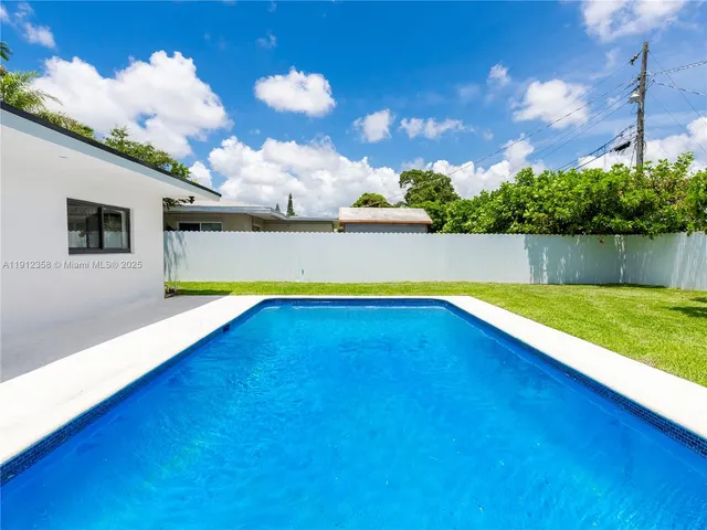 a view of house with swimming pool and yard