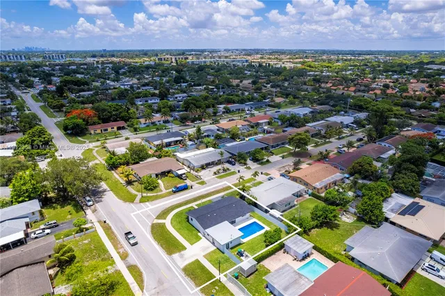 an aerial view of residential houses with outdoor space and trees