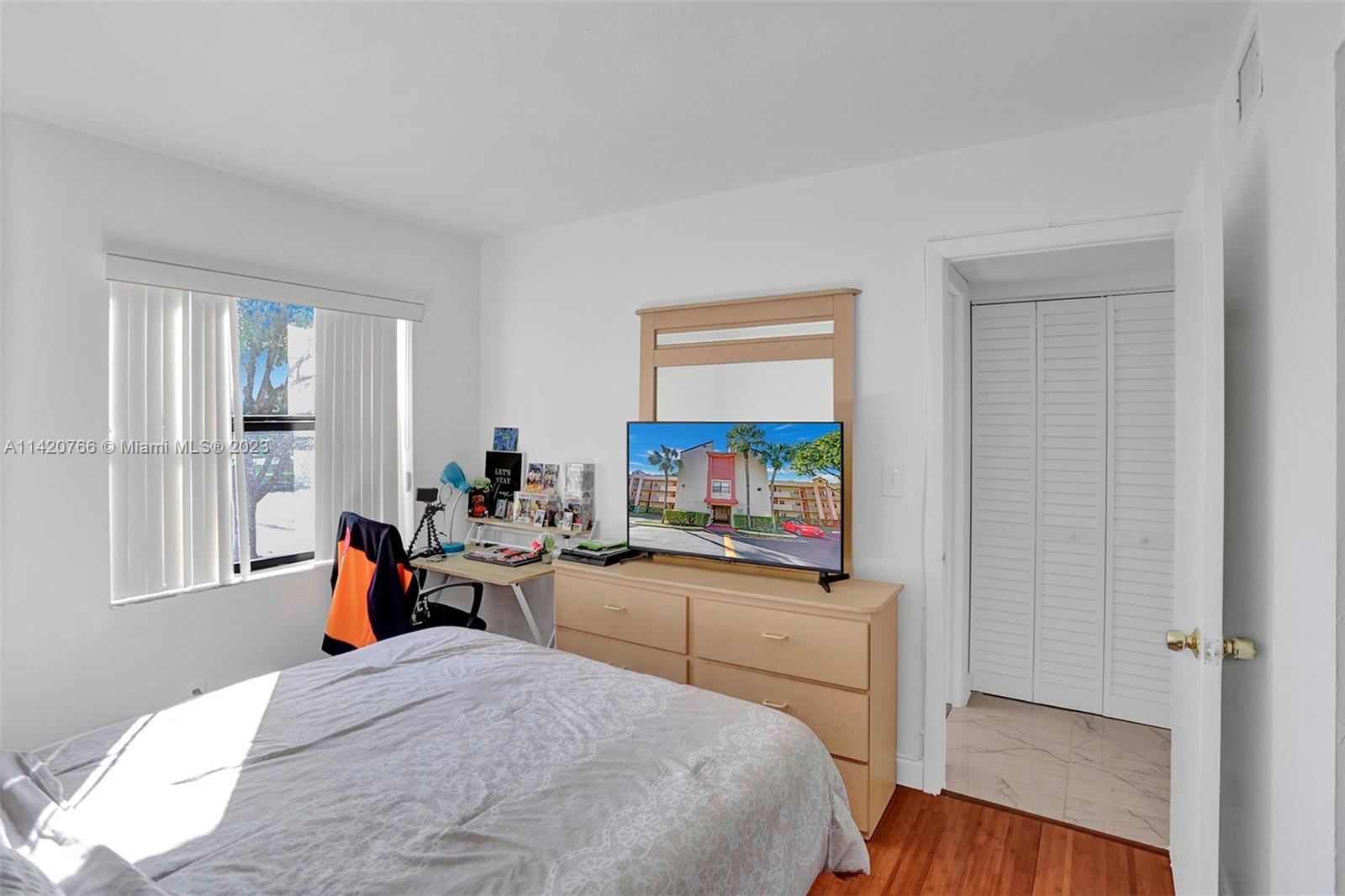 3410 Foxcroft Road, Unit 202 Miramar, FL 33025 - Photo 28 of 35 a bedroom with a bed and a flat tv screen on the dresser