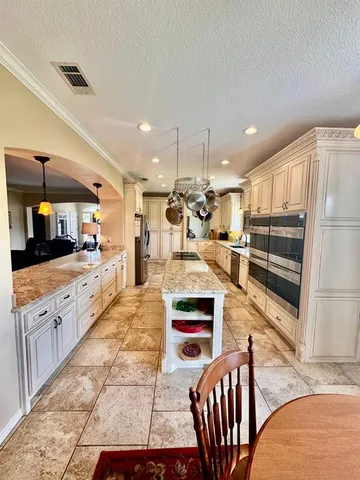 a large kitchen with stainless steel appliances kitchen island granite countertop a table chairs in it and a wooden floor