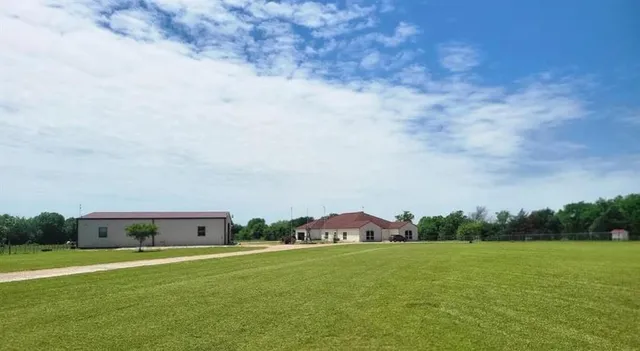 a view of a lush green field with some trees in the background