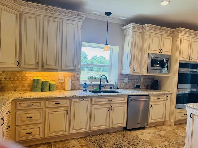 a kitchen with stainless steel appliances granite countertop a sink window and cabinets