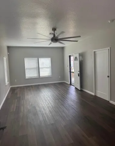 an empty room with wooden floor chandelier and windows