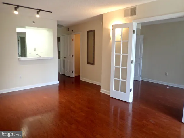 an empty room with wooden floor and windows