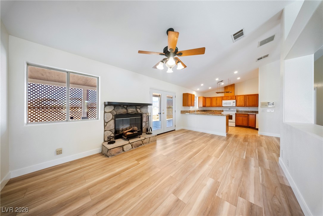 2420 Tough Boy Road Pahrump, NV 89060 - Photo 11 of 54 Unfurnished living room with light wood finished floors, a stone fireplace, lofted ceiling, ceiling fan, and recessed lighting