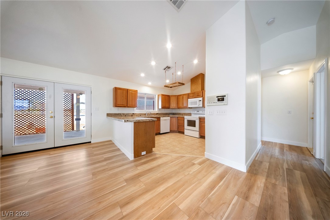 2420 Tough Boy Road Pahrump, NV 89060 - Photo 12 of 54 Kitchen featuring white appliances, a peninsula, light wood-style floors, french doors, and high vaulted ceiling