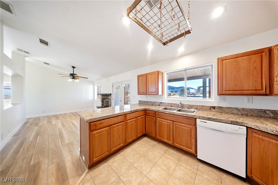 2420 Tough Boy Road Pahrump, NV 89060 - Photo 15 of 54 Kitchen with white dishwasher, a peninsula, a ceiling fan, brown cabinets, and light wood-type flooring
