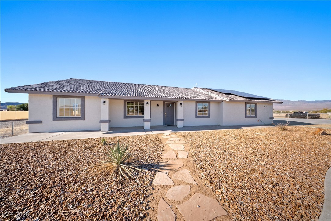 2420 Tough Boy Road Pahrump, NV 89060 - Photo 2 of 54 Single story home featuring a porch, roof mounted solar panels, and stucco siding