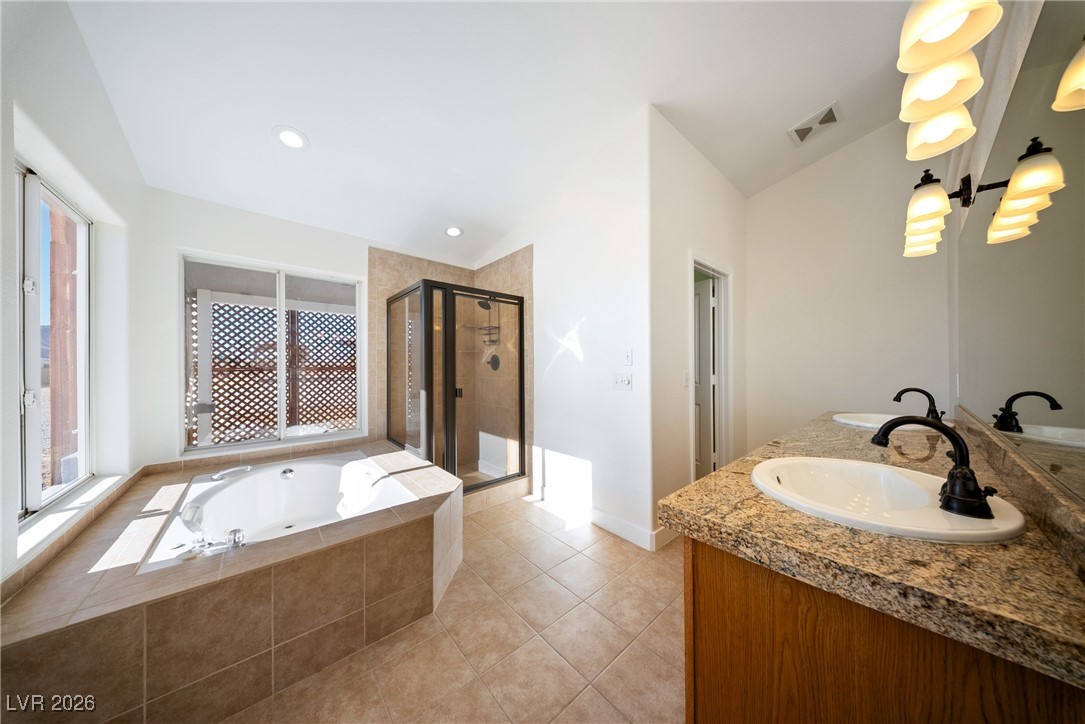 2420 Tough Boy Road Pahrump, NV 89060 - Photo 22 of 54 Full bathroom featuring a stall shower, vaulted ceiling, a jetted tub, double vanity, and tile patterned floors